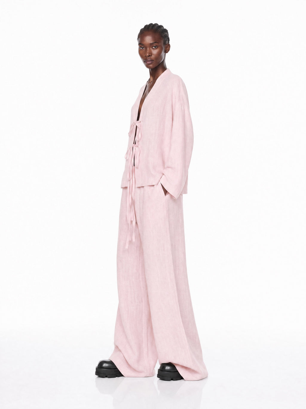 Model wearing a light pink outfit on a white background
