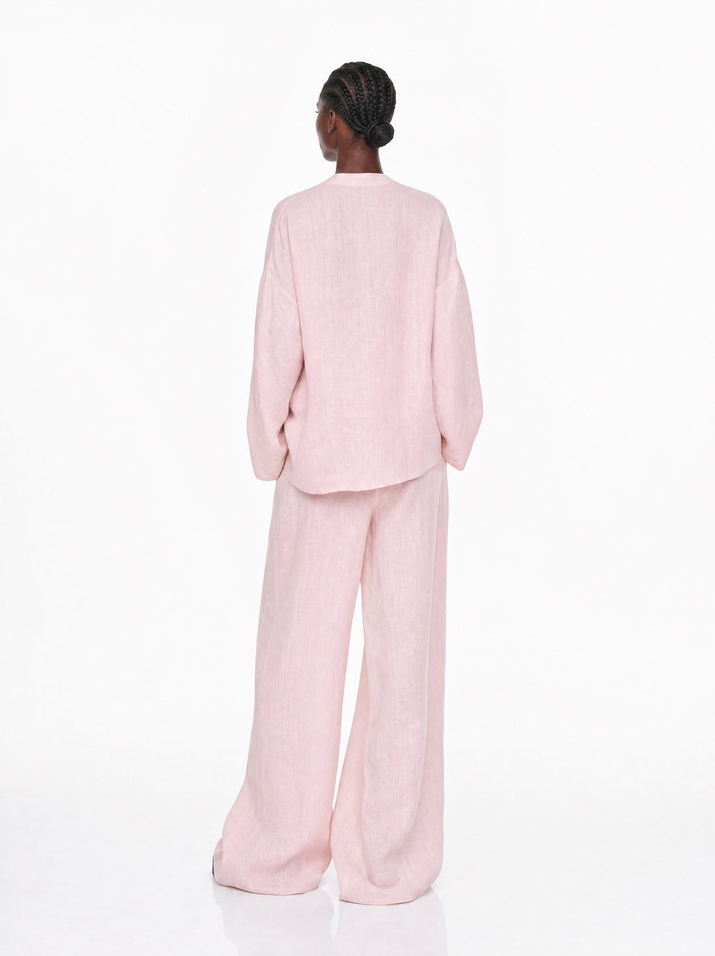 Person wearing a light pink suit on a white background